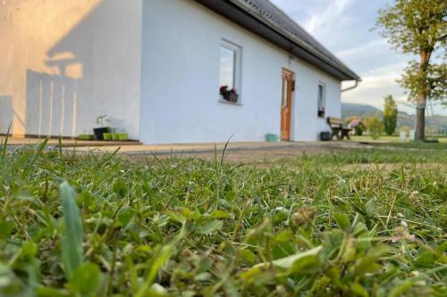 ein Grasfeld vor einem weißen Gebäude in der Unterkunft Grandma's House in Radlje ob Dravi