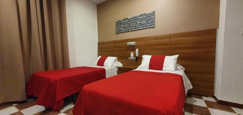 2 Betten in einem Zimmer mit roter und weißer Bettwäsche in der Unterkunft Hostal San Francisco in Cádiz