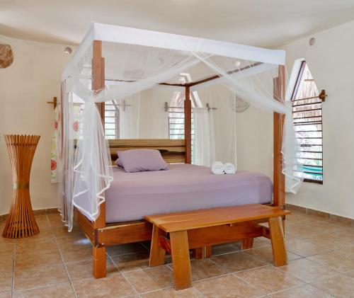 a bedroom with a canopy bed and a wooden bench at Villas Ecotucan in Bacalar