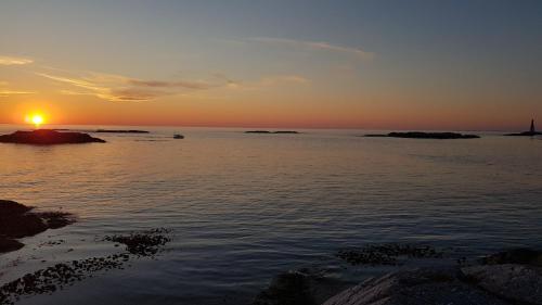 a sunset over a body of water with the sun setting at Sveggvika Guesthouse in Averoy