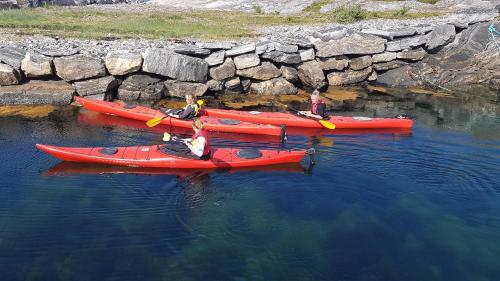 three people are in red kayaks in the water at Sveggvika Guesthouse in Averoy