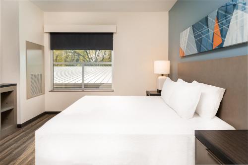 a white bedroom with a large bed and a window at Hyatt House Nashville Airport in Nashville