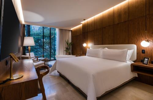メデジンにあるElcielo Hotel Luxury Medellinのベッドルーム(白い大型ベッド1台、デスク付)