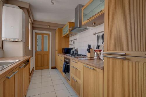 a kitchen with wooden cabinets and a stove top oven at Sunderland Self Catering 2 - Violet Cottage Free Parking in Sunderland