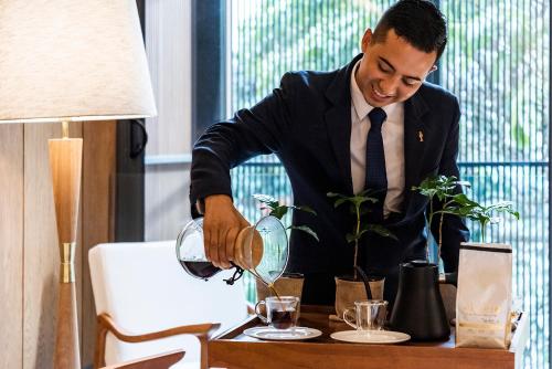 a man in a suit pouring a drink into a table at Elcielo Hotel Luxury Medellin in Medellín