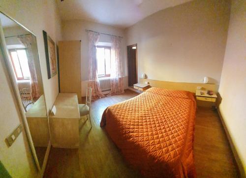 a bedroom with an orange bed and two windows at Bellavista Hotel & Osteria in Lamporecchio