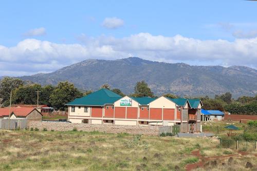 a large building in a field with mountains in the background at The 4 JS Bed and Breakfast Emali in Emali