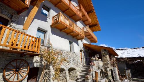 ein Gebäude mit einem Holzbalkon und einem Holzrad in der Unterkunft Maison Du-Noyer Chambres et Tables d'Hotes in Aosta