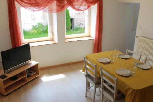 une salle à manger avec une table et une télévision dans l'établissement Gite de l'ancien Moulin, à Le Val-dʼAjol