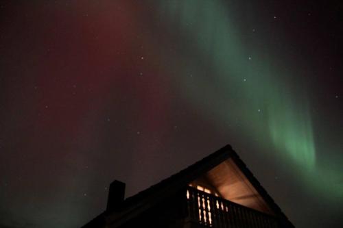 an image of the northern lights in the sky over a house at Sveggvika Guesthouse in Averoy