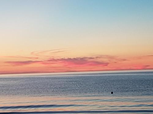 a sunset over the ocean with a person in the water at NCM Apartments Seaside Park in Kołobrzeg