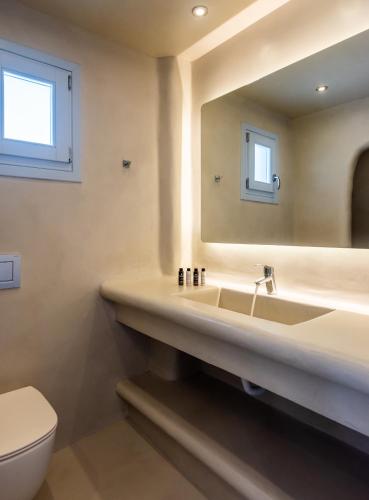 a bathroom with a sink and a toilet and a mirror at Plaka Suites in Plaka Milou