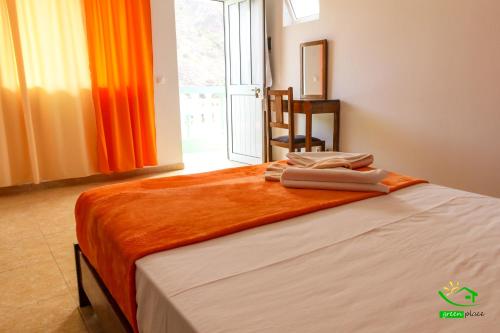 a bedroom with a bed with an orange blanket on it at Pousada Green Place in Ribeira Grande