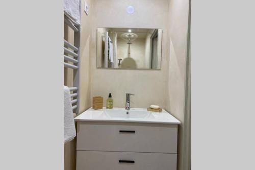 une salle de bain avec un lavabo blanc et un miroir dans l'établissement Appartement neuf et très calme, à Avignon