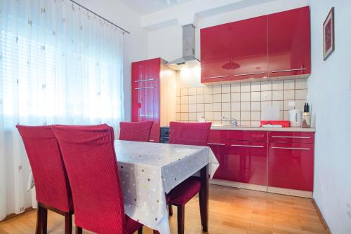 a kitchen with red cabinets and a table with red chairs at Apartments Vesna in Slunj