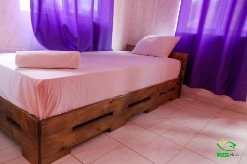 a bed in a room with purple curtains at Pousada Green Place in Ribeira Grande