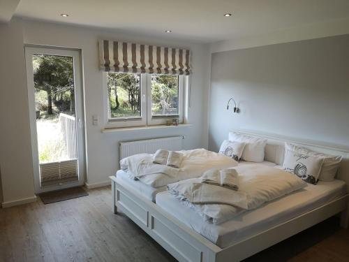 ヴェスターラントにあるGartenwohnung-Landhaus-Tadsenの白いベッドルーム(白いシーツと枕付きのベッド1台付)