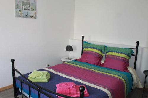 Gite de l'ancien Moulin في لو فال ديه آجول: غرفة نوم مع سرير مع بطانيات ووسائد ملونة