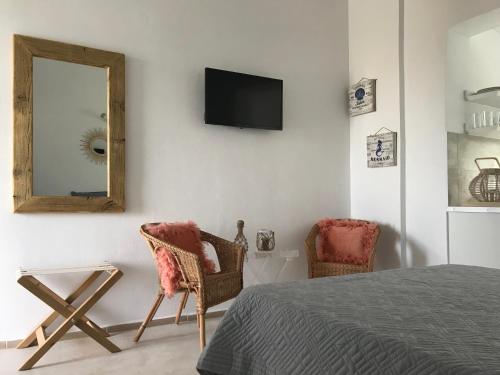 a bedroom with a bed and a mirror and chairs at Bay View Villas in Methoni