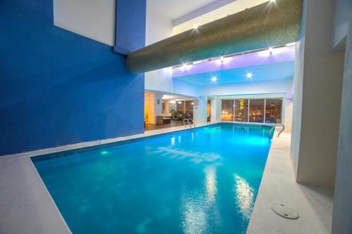 an indoor swimming pool with blue water in a building at La Quinta by Wyndham Puebla Palmas Angelopolis in Puebla