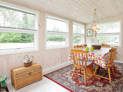 a dining room with a table and chairs and windows at 4 person holiday home in Hals in Hals