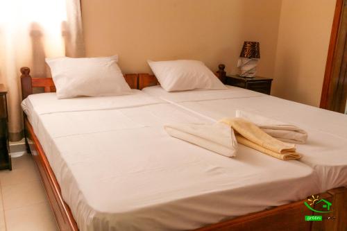 a bed with white sheets and two towels on it at Pousada Green Place in Ribeira Grande