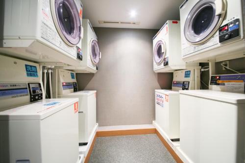 a laundry room with white washers and dryers at Hotel Wing International Sagamihara in Sagamihara