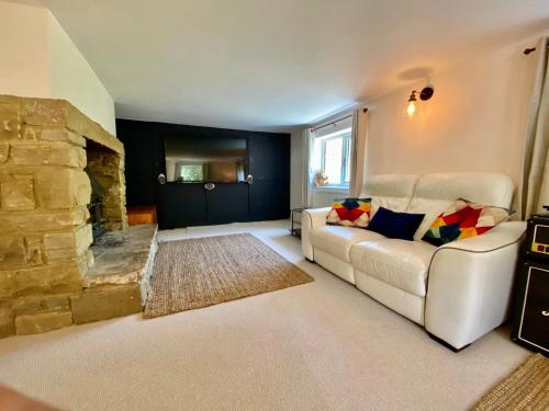 a living room with a white couch and a stone fireplace at Beautiful Character 5 Bedroom Dorset Thatched Cottage - Great Location - Garden - Parking - Fast WiFi - Smart TV - Newly decorated - sleeps up to 10! Only 18 mins drive to Sandbanks Beach! Close to Bournemouth & Poole in Wimborne Minster