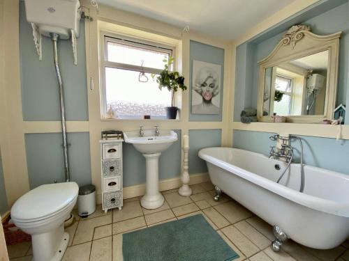 a bathroom with a tub and a toilet and a sink at Beautiful Character 5 Bedroom Dorset Thatched Cottage - Great Location - Garden - Parking - Fast WiFi - Smart TV - Newly decorated - sleeps up to 10! Only 18 mins drive to Sandbanks Beach! Close to Bournemouth & Poole in Wimborne Minster