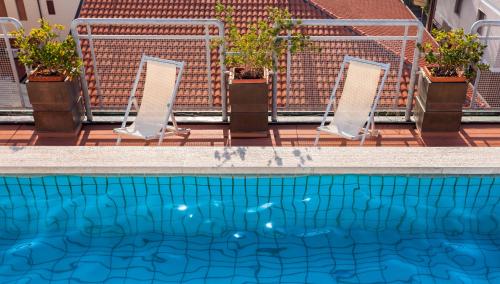 a swimming pool with two mirrors and potted plants at Hotel Da Vinci in Montecatini Terme