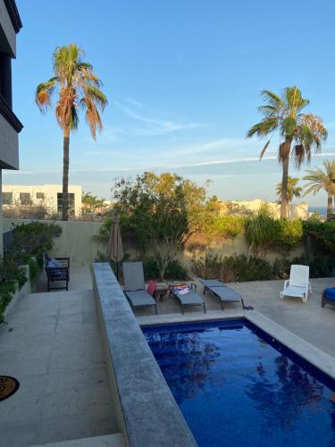 ein Swimmingpool mit Terrasse und Palmen in der Unterkunft Spectacular Vacation Home Ocean View Walk to Beach in Cabo San Lucas