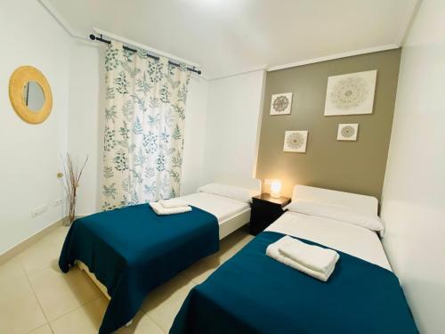 two beds in a room with blue and white at M & B Beach Apartment in Valencia