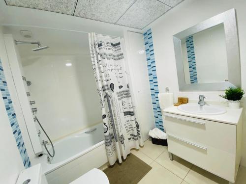 a white bathroom with a shower and a sink at M & B Beach Apartment in Valencia