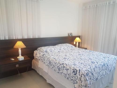 a bedroom with a bed and two night stands with lamps at Praia do Forte- Iberostar- Ap Luxuoso 3 qts in Mata de Sao Joao