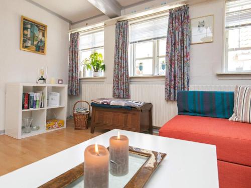 a living room with a red couch and a table with candles at 3 person holiday home in r sk bing in Ærøskøbing