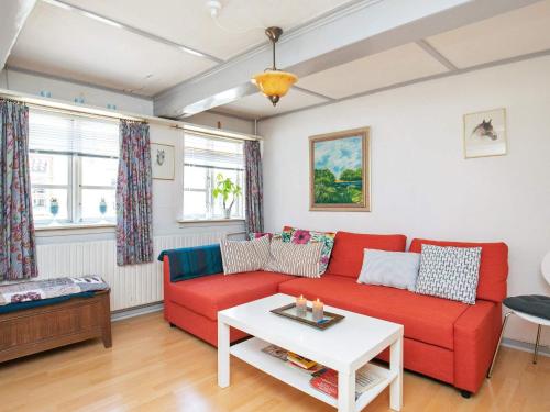 a living room with a red couch and a table at 3 person holiday home in r sk bing in Ærøskøbing