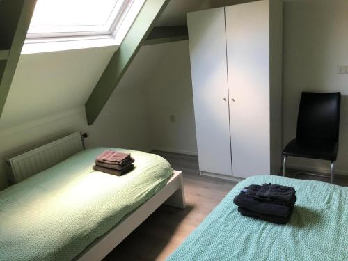 1 dormitorio con 2 camas, ventana y silla en Gastenverblijf Eichhorn, en Schijf