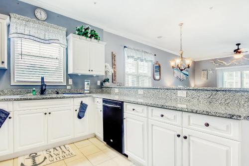 a kitchen with white cabinets and a black dishwasher at Coastal Escape in Myrtle Beach