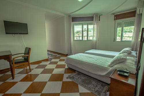 a bedroom with a bed and a desk and a television at Motel Gzenaya in Tangier