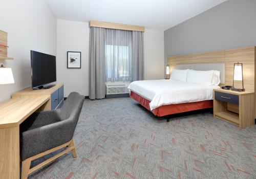 a hotel room with a bed and a flat screen tv at Candlewood Suites DFW West - Hurst by IHG in Hurst