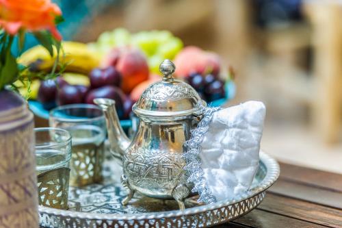 een zilveren theepot op een bord op een tafel bij Riad Beldi in Marrakesh