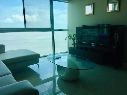 a living room with a glass coffee table and a television at River View Suites Guayaquil in Guayaquil