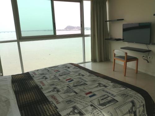 a bedroom with a bed and a television and a chair at River View Suites Guayaquil in Guayaquil