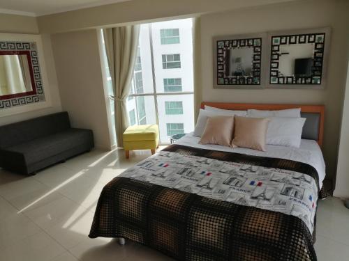 a bedroom with a bed and a couch and a window at River View Suites Guayaquil in Guayaquil