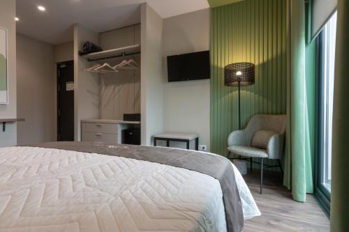 1 dormitorio con 1 cama blanca y 1 silla en Solarena Bistrot en Barreiros