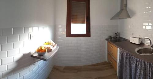 una cocina con fregadero y un bol de fruta en una barra en Apartamentos El Arenal, en Acebo