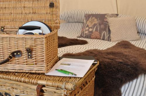a basket with a pen and a notebook on a bed at Immaculate and cosy Bell tent in Shaftesbury UK in Shaftesbury