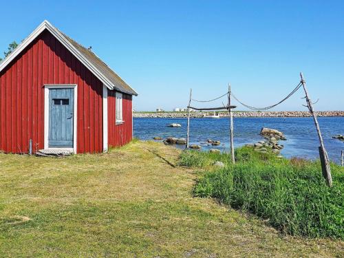 une grange rouge assise à côté d'une masse d'eau dans l'établissement 6 person holiday home in S LVESBORG, à Sölvesborg