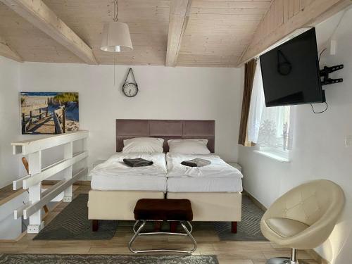 a bedroom with a bed and a television and a chair at Villa Promenada in Międzyzdroje