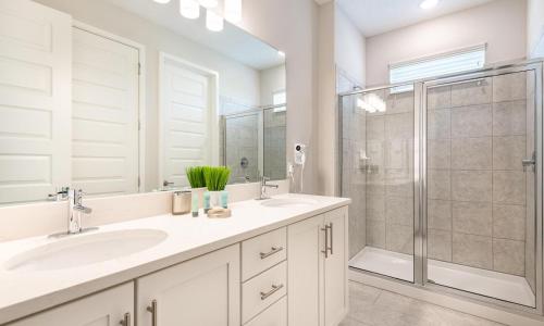 a white bathroom with two sinks and a shower at Serene Vibrant 4 Bdrm Villa with Games Room at Encore in Orlando
